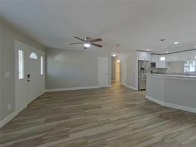 a view of an empty room with kitchen and a window