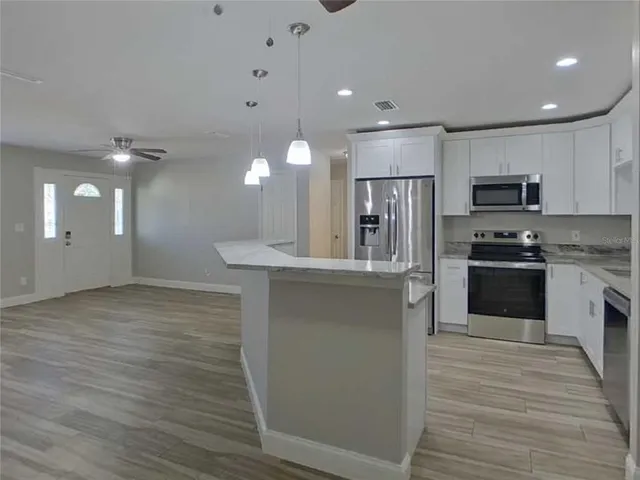 a large kitchen with kitchen island a sink stainless steel appliances and cabinets