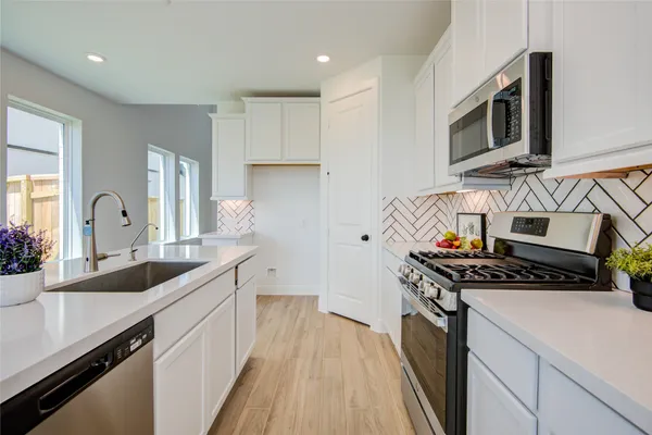 a kitchen with stainless steel appliances a sink dishwasher stove microwave and cabinets