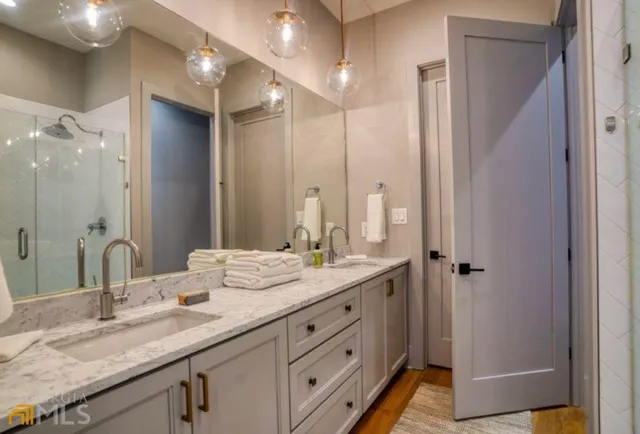 a bathroom with a granite countertop double vanity sink and mirror