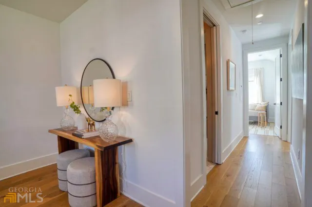 a view of a hallway with wooden floor door and a bathroom