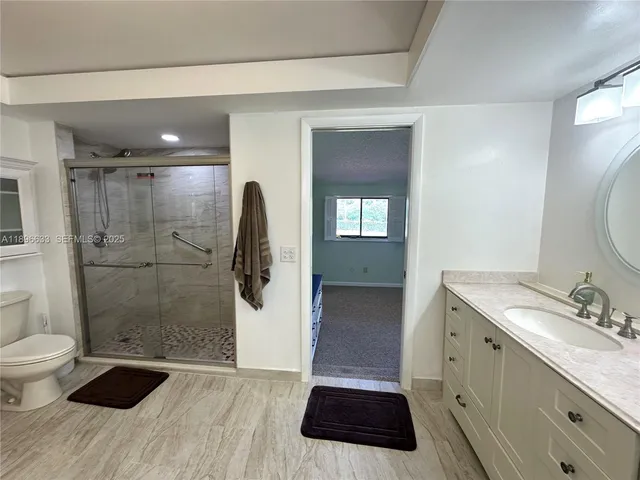 a bathroom with a granite countertop sink toilet and shower