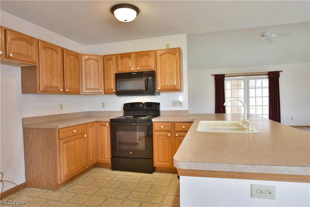 2033 East River Road, Unit 11 Newton Falls, OH 44444 - Photo 7 of 35 Kitchen with brown cabinets, black appliances, light countertops, light tile floors, and ceiling fan