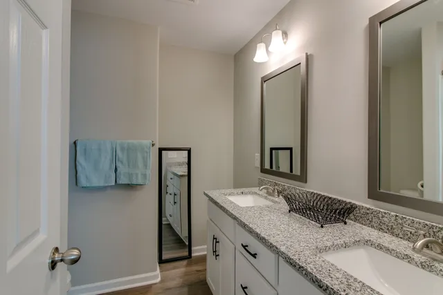 a bathroom with a granite countertop double vanity sink and mirror