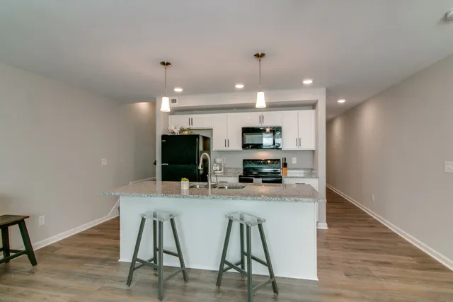 a kitchen with stainless steel appliances a dining table chairs microwave and stove top oven