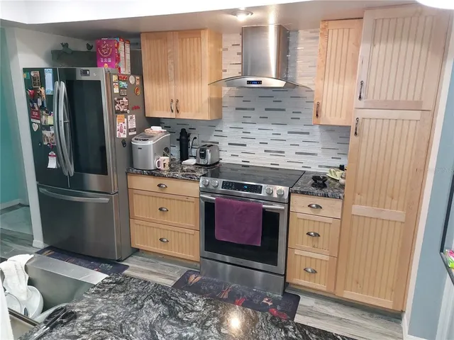 a kitchen with stainless steel appliances granite countertop a refrigerator and a stove