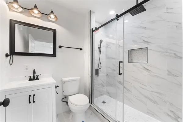 a bathroom with a toilet shower sink and mirror