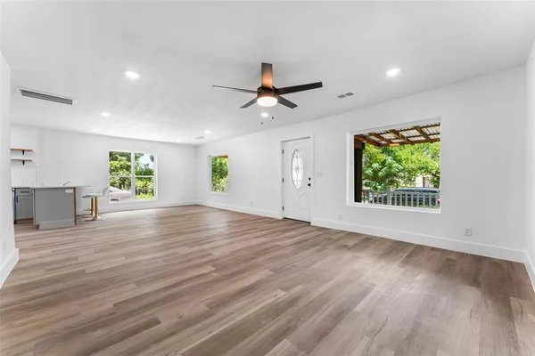 a view of an empty room with a window and wooden floor