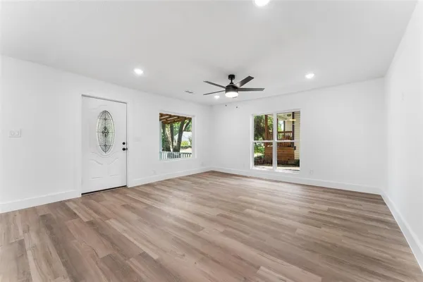 a view of an empty room with a window and wooden floor