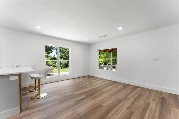 a view of an empty room with a window and wooden floor
