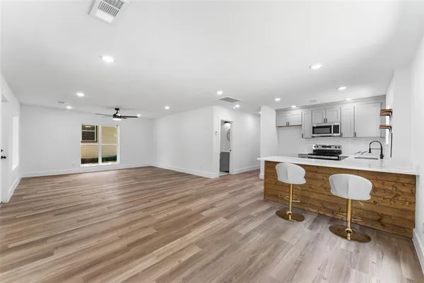 a view of kitchen with kitchen island wooden floors appliances and dining table