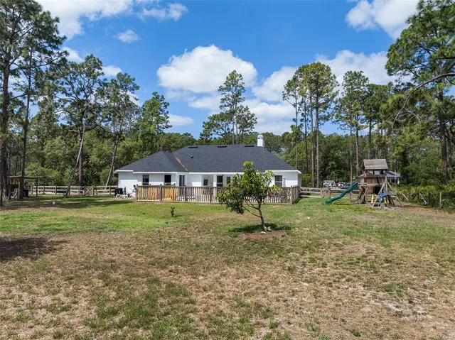 a view of a wooden house with a yard and large trees