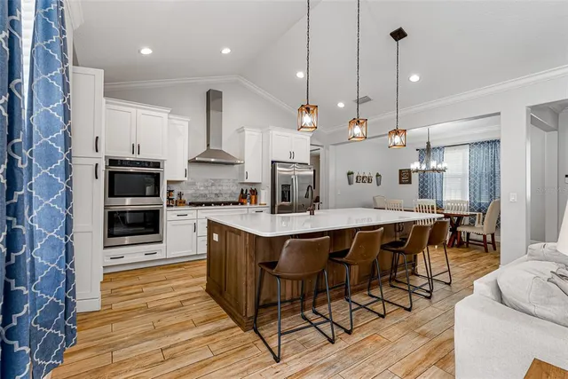 a kitchen with stainless steel appliances a dining table chairs stove and cabinets