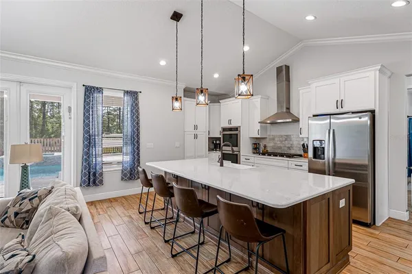 a open kitchen with stainless steel appliances granite countertop a kitchen island a stove a table and chairs
