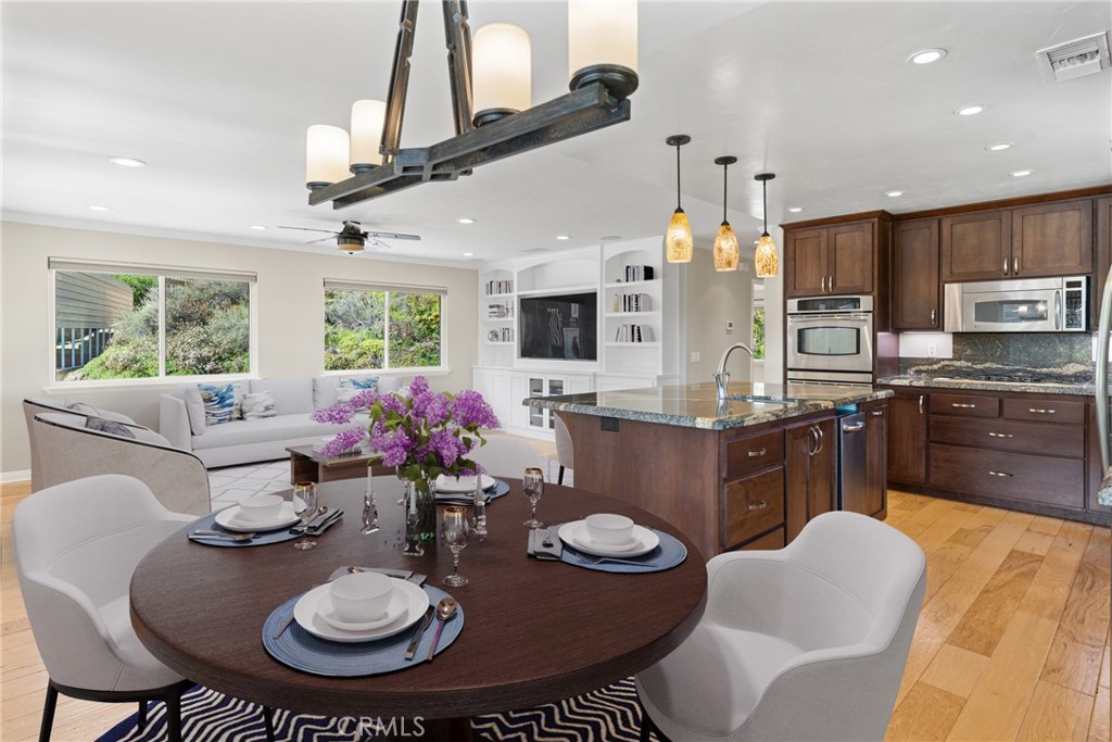 30300 Live Oak Canyon Road Redlands, CA 92373 - Photo 44 of 67 a kitchen with stainless steel appliances kitchen island granite countertop a stove a sink dishwasher a dining table and chairs with wooden floor