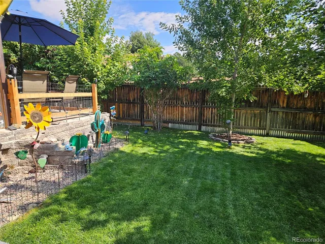a view of a backyard with table and chairs under an umbrella with wooden fence