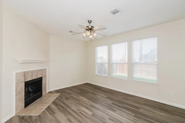 a view of an empty room with wooden floor and a fireplace