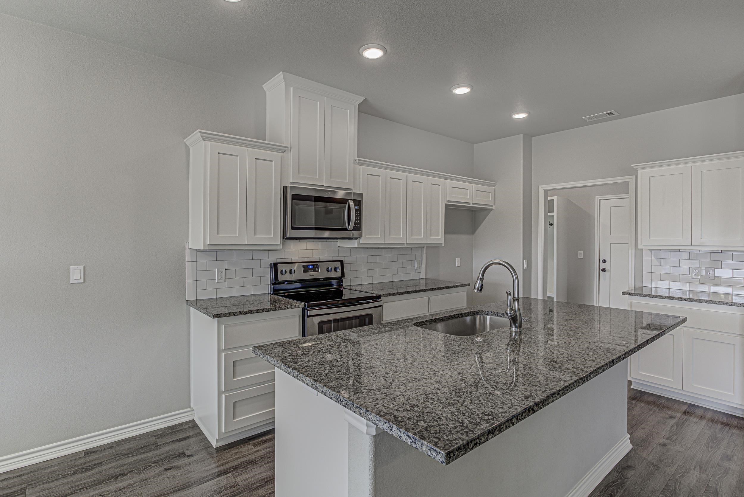 141 Rylee Road Burnet, TX 78611 - Photo 12 of 26 a kitchen with kitchen island granite countertop a sink a counter top space appliances and cabinets