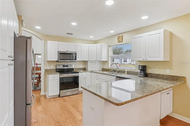 a kitchen with stainless steel appliances granite countertop a stove a sink and a refrigerator