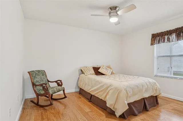 an empty room with kitchen view and a ceiling fan