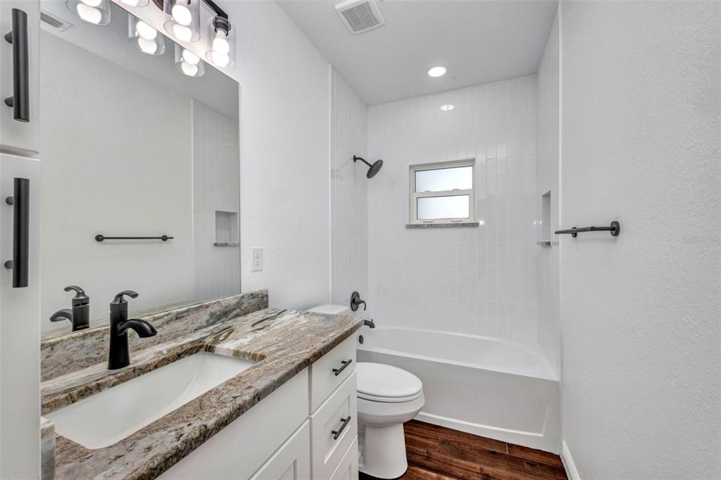 409 Carmalita Street, Unit 111 & 112 Punta Gorda, FL 33950 - Photo 13 of 75 a bathroom with a granite countertop sink a toilet a mirror and shower