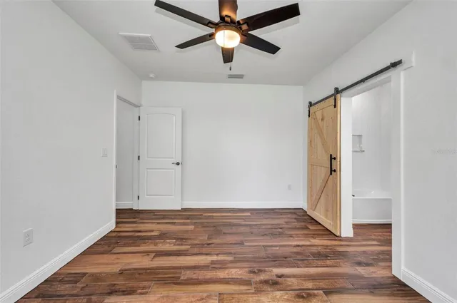 an empty room with wooden floor ceiling fan and windows