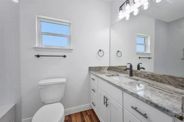 a bathroom with a granite countertop sink a toilet and shower