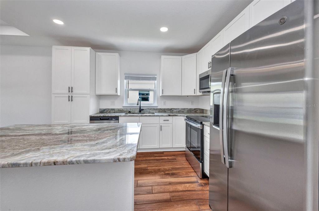 409 Carmalita Street, Unit 111 & 112 Punta Gorda, FL 33950 - Photo 39 of 75 a kitchen with granite countertop stainless steel appliances and white cabinets