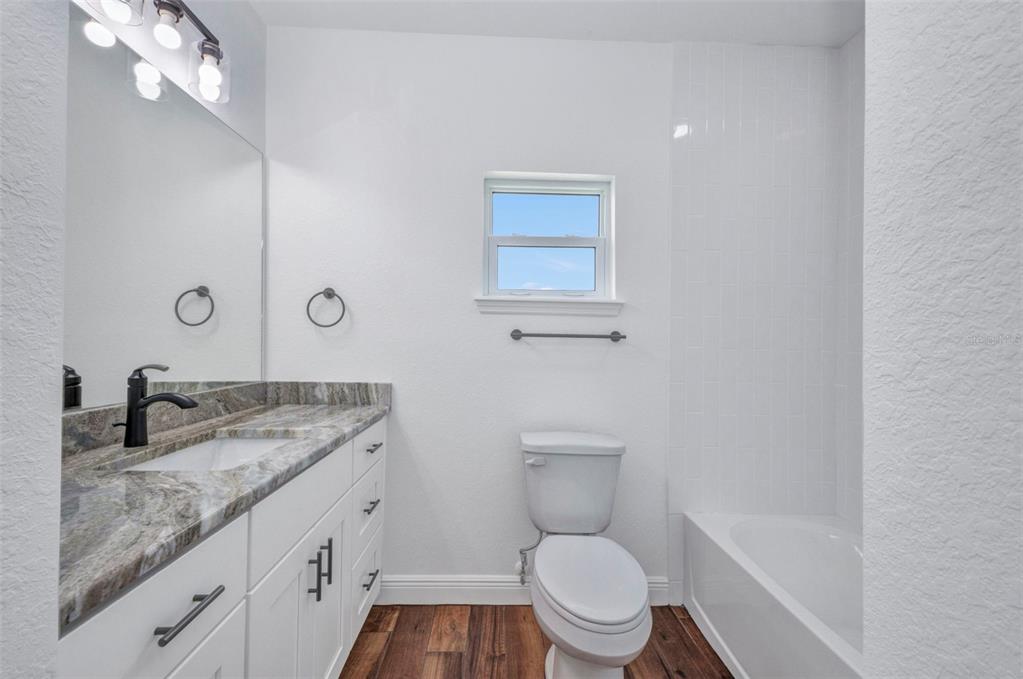 409 Carmalita Street, Unit 111 & 112 Punta Gorda, FL 33950 - Photo 53 of 75 a bathroom with a granite countertop toilet a sink and a mirror