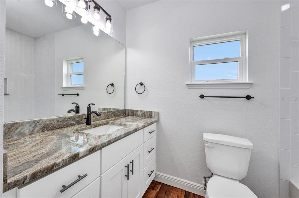 409 Carmalita Street, Unit 111 & 112 Punta Gorda, FL 33950 - Photo 54 of 75 a bathroom with a granite countertop toilet sink and mirror