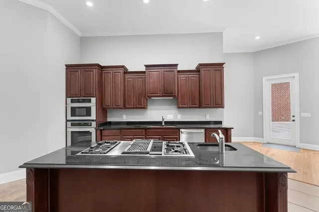 a kitchen with stainless steel appliances granite countertop a stove a sink and a microwave