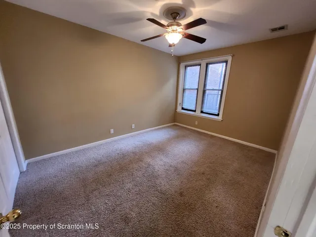 an empty room with windows and fan