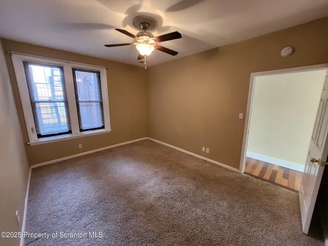 an empty room with a chandelier fan and windows