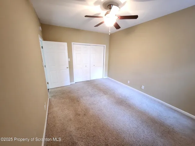 an empty room with a chandelier fan and windows