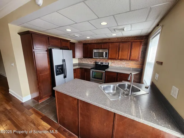 a kitchen with stainless steel appliances granite countertop a sink a stove counter space and refrigerator