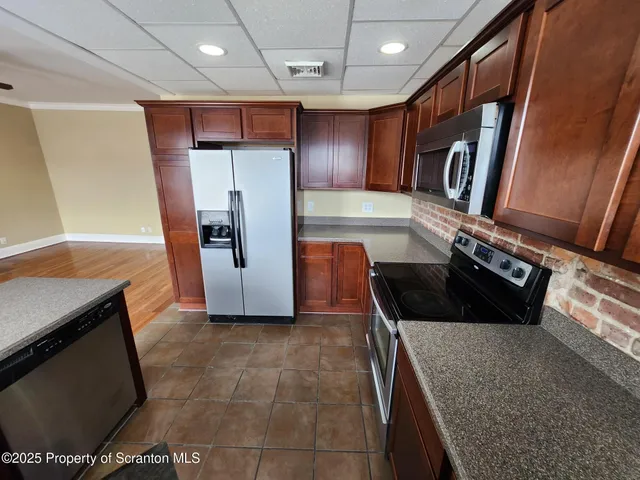 a kitchen with stainless steel appliances granite countertop a sink a stove a microwave a refrigerator and cabinets