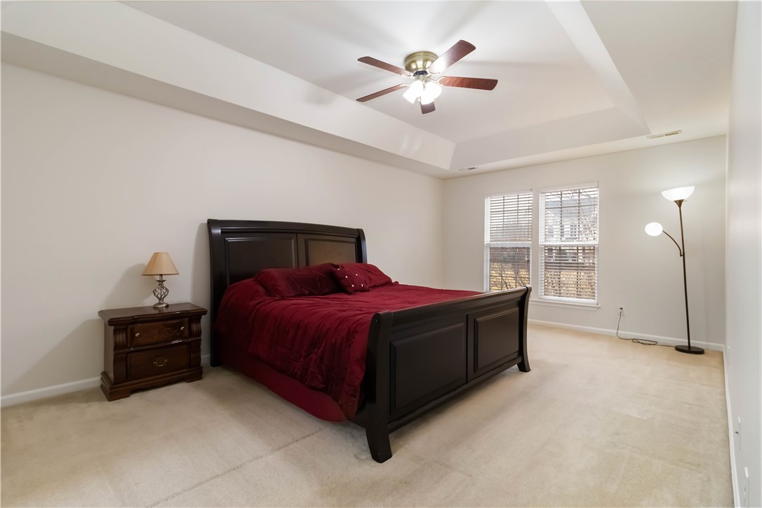 215 Ridge Bay Court Greenville, SC 29611 - Photo 26 of 35 This spacious bedroom features a tray ceiling and bright windows, creating a serene and inviting atmosphere.
