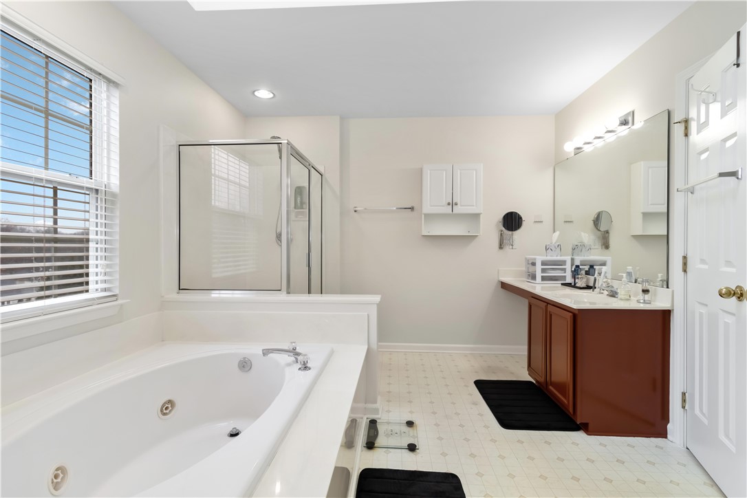 215 Ridge Bay Court Greenville, SC 29611 - Photo 28 of 35 Bright primary bathroom features a soaking tub, glass-enclosed shower, and a vanity with ample counter space.