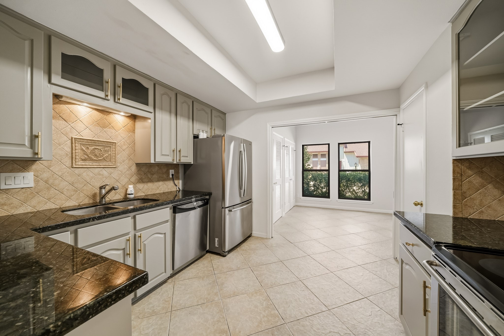 1746 South Gessner Road Houston, TX 77063 - Photo 9 of 25 Bright kitchen with modern granite countertops, stainless steel appliances, and ample cabinet space, opening to a cozy dining area filled with natural light.