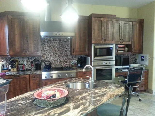 a kitchen with stainless steel appliances granite countertop a sink stove and cabinets