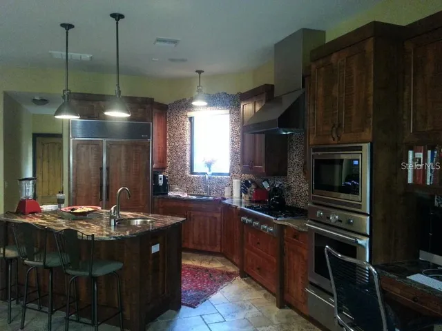 a kitchen with kitchen island a counter top space appliances and a chandelier