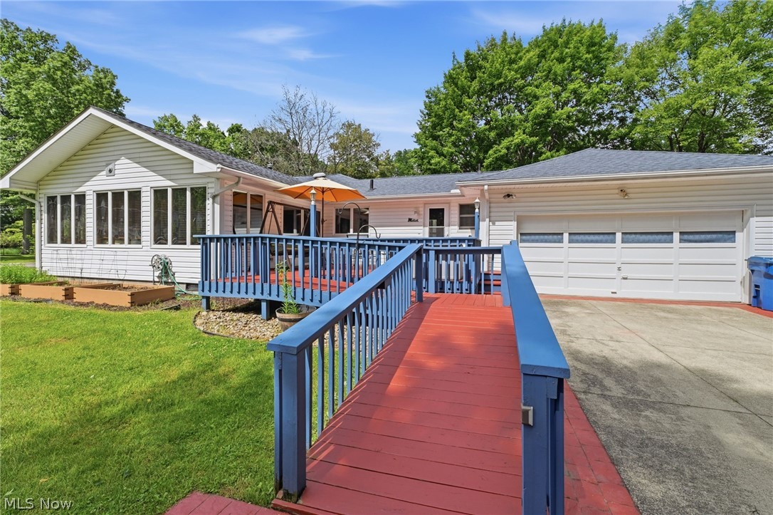 1499 Morris Road Kent, OH 44240 - Photo 39 of 41 Exterior featuring white siding, a sunroom with multiple windows, a rear deck, a paved driveway, and an attached garage with panel doors