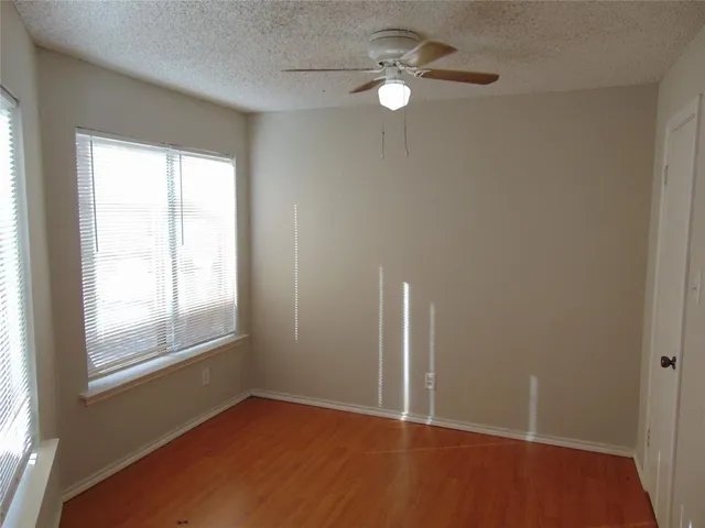 an empty room with windows and fan
