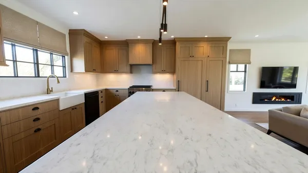 a large white kitchen with kitchen island a large counter top space a sink stainless steel appliances and cabinets