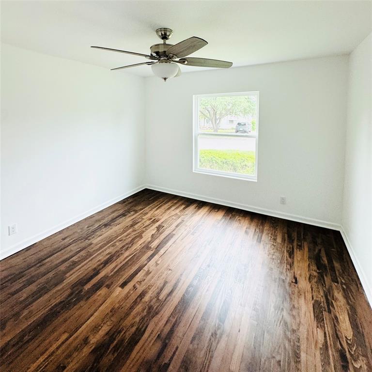 6442 Latta Street Dallas, TX 75227 - Photo 11 of 12 an empty room with wooden floor chandelier fan and windows