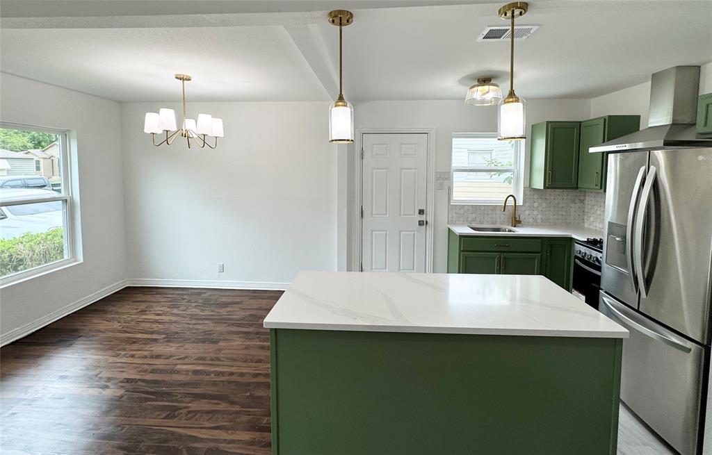 6442 Latta Street Dallas, TX 75227 - Photo 6 of 12 a kitchen with kitchen island a refrigerator a stove a sink dishwasher a oven with wooden floor and cabinets