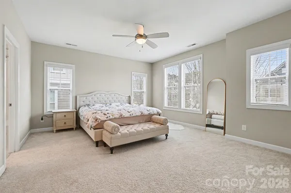 a spacious bedroom with a bed chairs and window