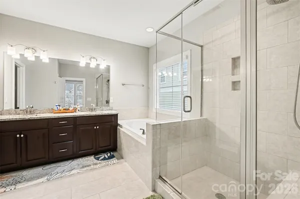 a spacious bathroom with a granite countertop sink a mirror a shower and a bathtub