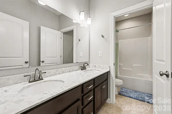 a bathroom with a granite countertop sink a toilet and shower