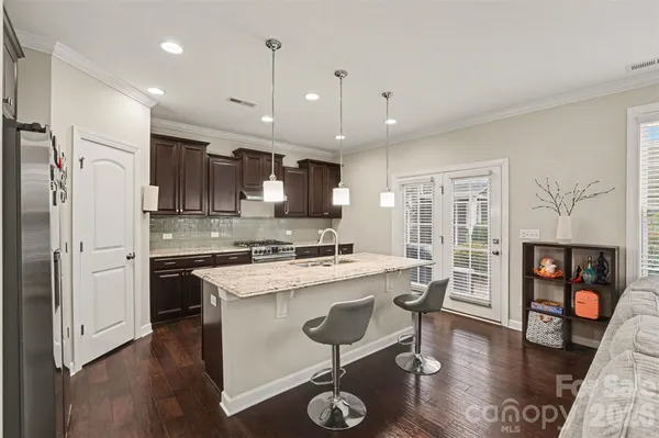 a kitchen with stainless steel appliances granite countertop a refrigerator a stove top oven a sink dishwasher and white cabinets with wooden floor